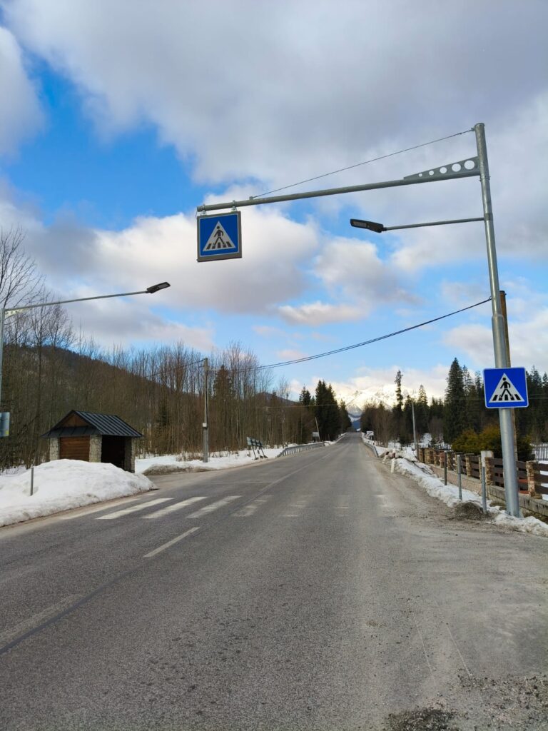 Skrzyżowanie drogi przed remontem, ze słabo widocznymi pasami dla pieszych i starym asfaltem Križovatka pred rekonštrukciou, so slabo viditeľnými priechodmi pre chodcov a starým asfaltom