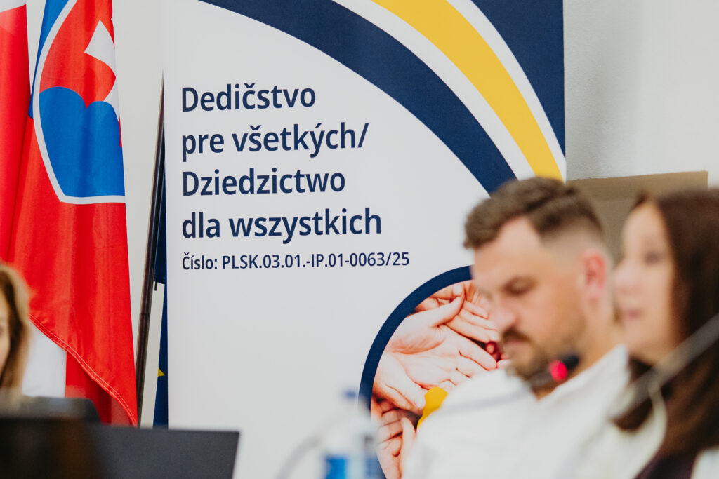 Baner promocyjny projektu z napisem w języku słowackim i polskim „Dedičstvo pre všetkých / Dziedzictwo dla wszystkich” oraz numerem projektu, obok stoją flagi Polski i Słowacji. Propagačný banner projektu s nápisom v slovenčine a poľštine „Dedičstvo pre všetkých / Dziedzictwo dla wszystkich“ a číslom projektu, vedľa stoja vlajky Poľska a Slovenska.